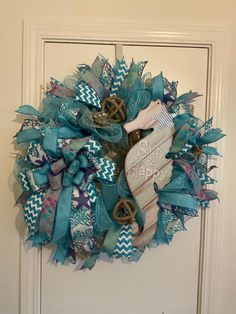 a blue and white wreath with the words sea & happy written on it in front of a door