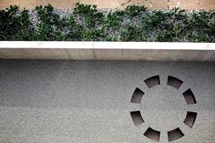 a circular cut out on the side of a building next to a planter filled with green leaves