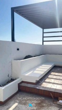 an empty patio with white walls and wood flooring under a pergolated roof