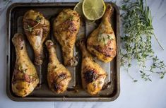 chicken legs with herbs and lemon on a baking sheet