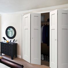 a bedroom with white closet doors and a mirror on the wall next to a bed