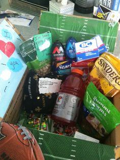 an open box filled with snacks and other items sitting on the floor next to a football