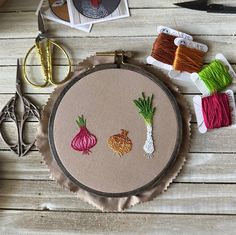 some thread and scissors are sitting on a table with an embroidery project in the shape of vegetables