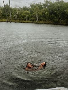 a person floating in the water on top of a body of water next to trees