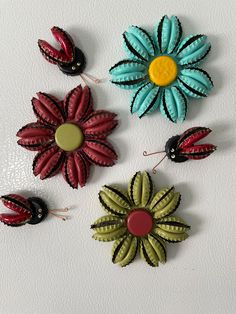 four different colored flowers on a white surface