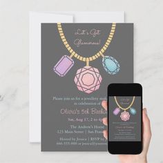 a person holding up a cell phone next to a card with an image of jewelry on it