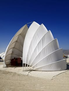 several large white umbrellas sitting on top of a sandy beach