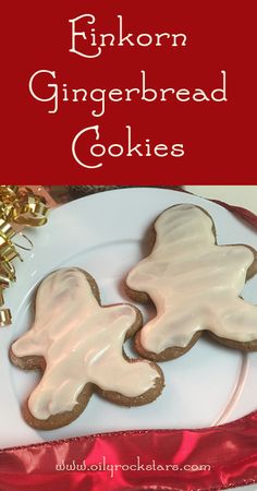 two decorated gingerbread cookies on a white plate with red ribbon and gold decorations in the background