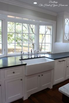 a kitchen with white cabinets and black counter tops, along with an island in the middle