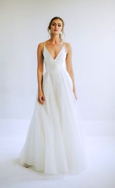 a woman in a white wedding dress standing on a white background with her eyes closed