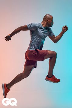 a man is jumping in the air while wearing red shorts and a gray t - shirt