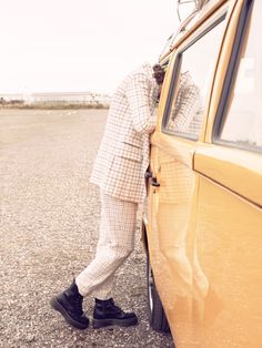 a man leaning on the door of a yellow car with his head in the window