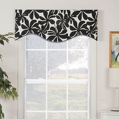 a window with a black and white flowered valance