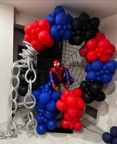 a spiderman balloon sculpture is surrounded by red, white and blue balloons