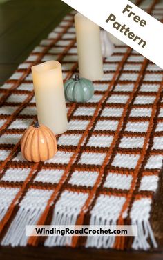 two candles sitting on top of a table next to a white and orange checkered cloth