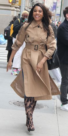 a woman is walking down the street in a trench coat and leopard print tights