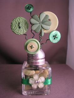 a glass bottle with buttons and flowers in it