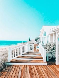 a wooden deck next to the ocean with white railings