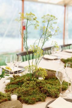 the table is set with moss and wine glasses