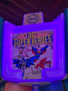 the dc super hero sign is lit up in purple and blue lights, as well as other items