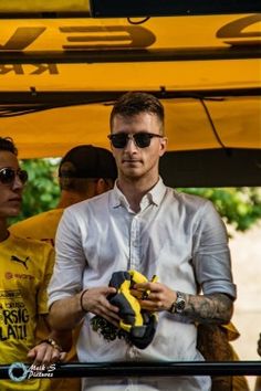 a man in sunglasses holding a yellow and black object while standing next to other people