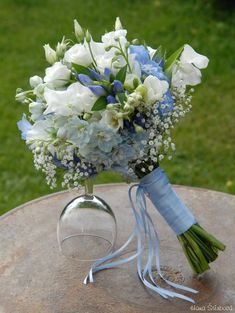 a bouquet of white and blue flowers sitting on top of a table