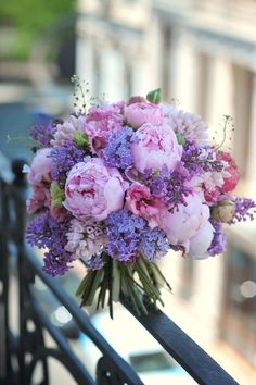 a bouquet of pink and purple flowers on a railing