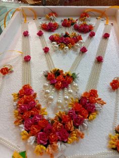 an assortment of necklaces and bracelets in a white box with flowers on it