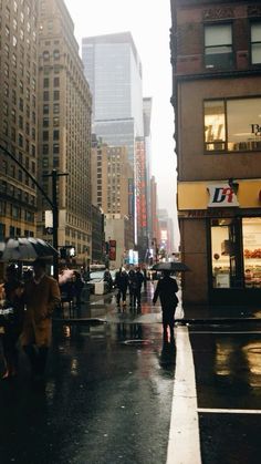 people are walking down the street in the rain