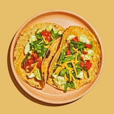 two tacos are sitting on a plate with lettuce, tomatoes and cheese