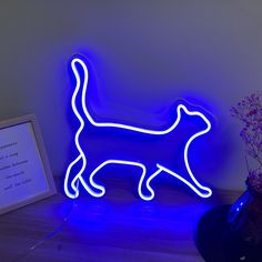 a blue neon cat standing next to a vase with flowers in it on a table