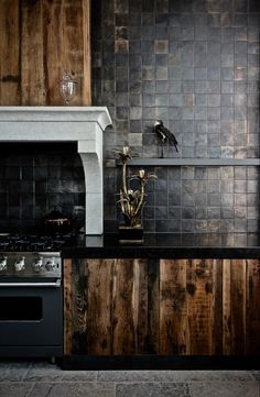 a kitchen with black counter tops and wood paneling on the wall, along with a stove top oven