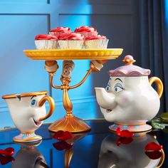 beauty and the beast tea set with cupcakes on a cake stand in front of it