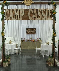 a sign that says camp cassie on the side of a table with white chairs