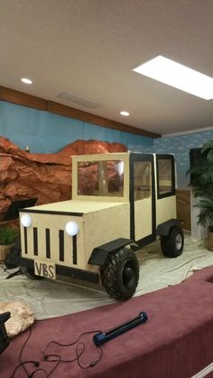 a truck made out of cardboard sitting on top of a table in front of a mural