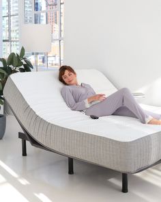 a woman laying on top of a mattress in a room