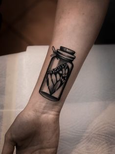 a person's arm with a tattoo on it that has a jar in it