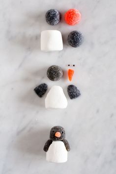 three marshmallows are arranged in the shape of a penguin and an orange carrot