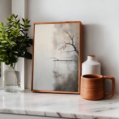 a painting on a shelf next to a vase with a plant in it and a mug