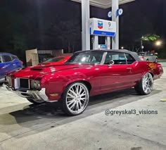 a red car parked in front of a gas station