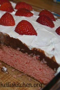 a strawberry cake with white frosting and strawberries on top is ready to be eaten