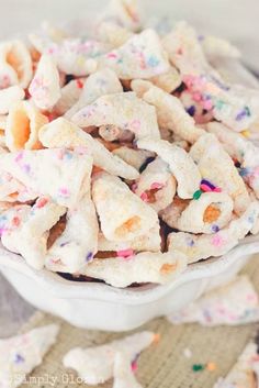 a white bowl filled with sprinkles next to a pile of cookies on top of a table