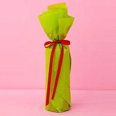 an origami wrapped in green paper and tied with red ribbon on pink background