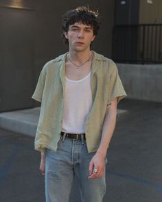 a young man standing in front of a building wearing jeans and a white t - shirt