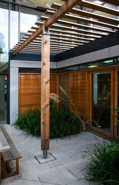 a wooden pergolan sitting on top of a patio next to a tall building