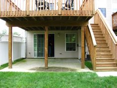 a back yard with stairs leading to the upper deck and second story door on one side