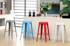 three different colored stools in front of a bar with wine glasses on the counter