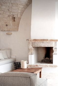 a living room with a fire place and couches in front of an arched wall