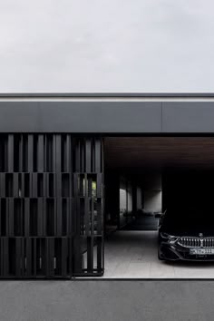 a black car parked in front of a garage with an open door on the side