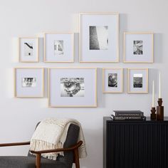 there are many pictures hanging on the wall above a chair and a table with candles